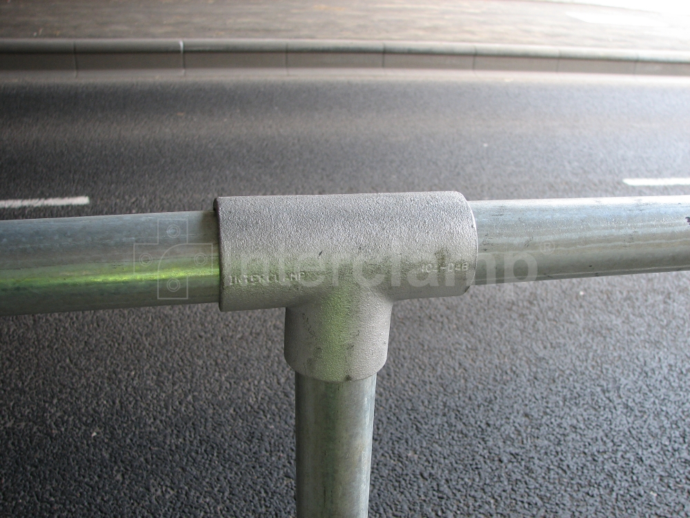 Pedestrians walking safely along a busy main road protected by Interclamp standard safety stanchion posts, demonstrating effective barrier solutions.